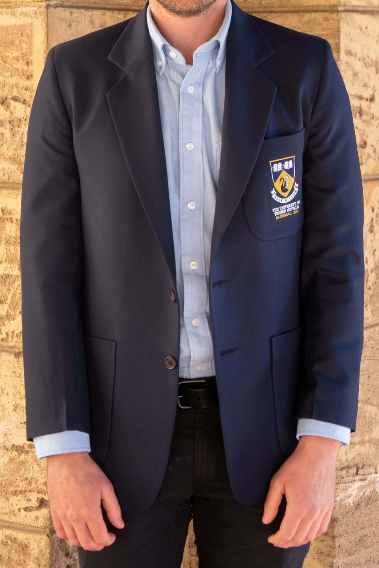 A front view of a man wearing the UWA Blues Blazer unbuttoned.